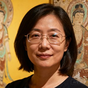 一位留着齐肩短发、佩戴细框眼镜的女性博物馆负责人的半身肖像，身后隐约可见敦煌壁画元素的装饰墙面